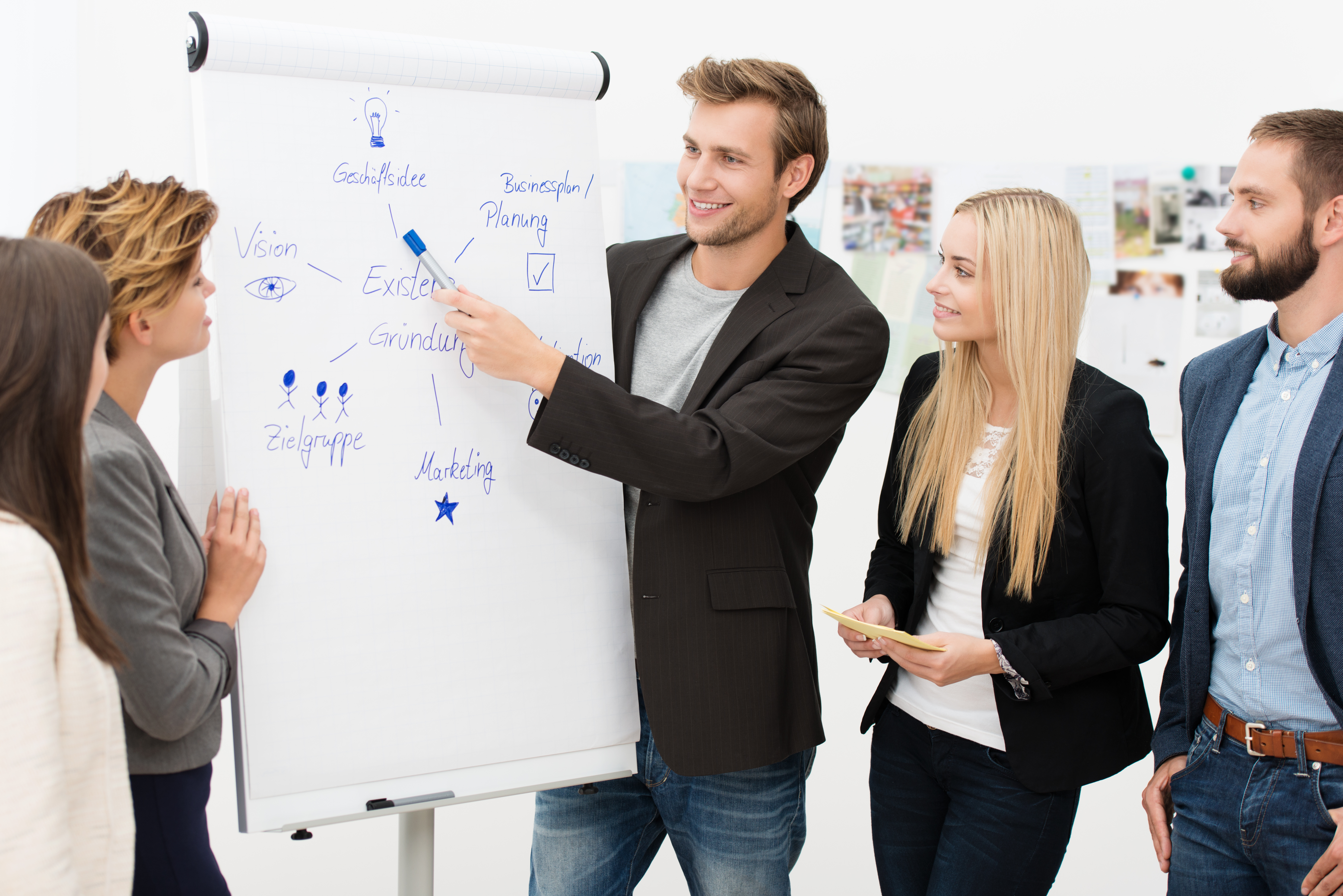 5 sodelavcev diskutira novo idejo, eden izmed njih je idejo narisal na papirnato tablo