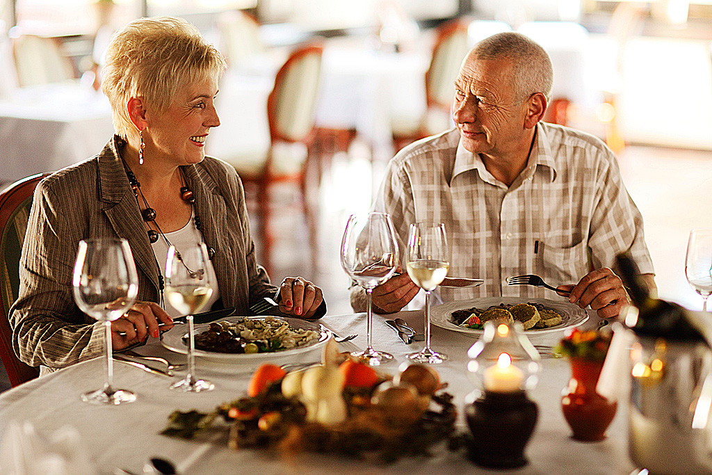 Par v starejših letih sedi za obloženo mizo in ob sveči večerja