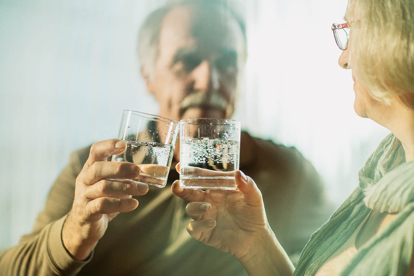 Starejši par nazdravlja ob kozarcu zdravilne mineralne vode