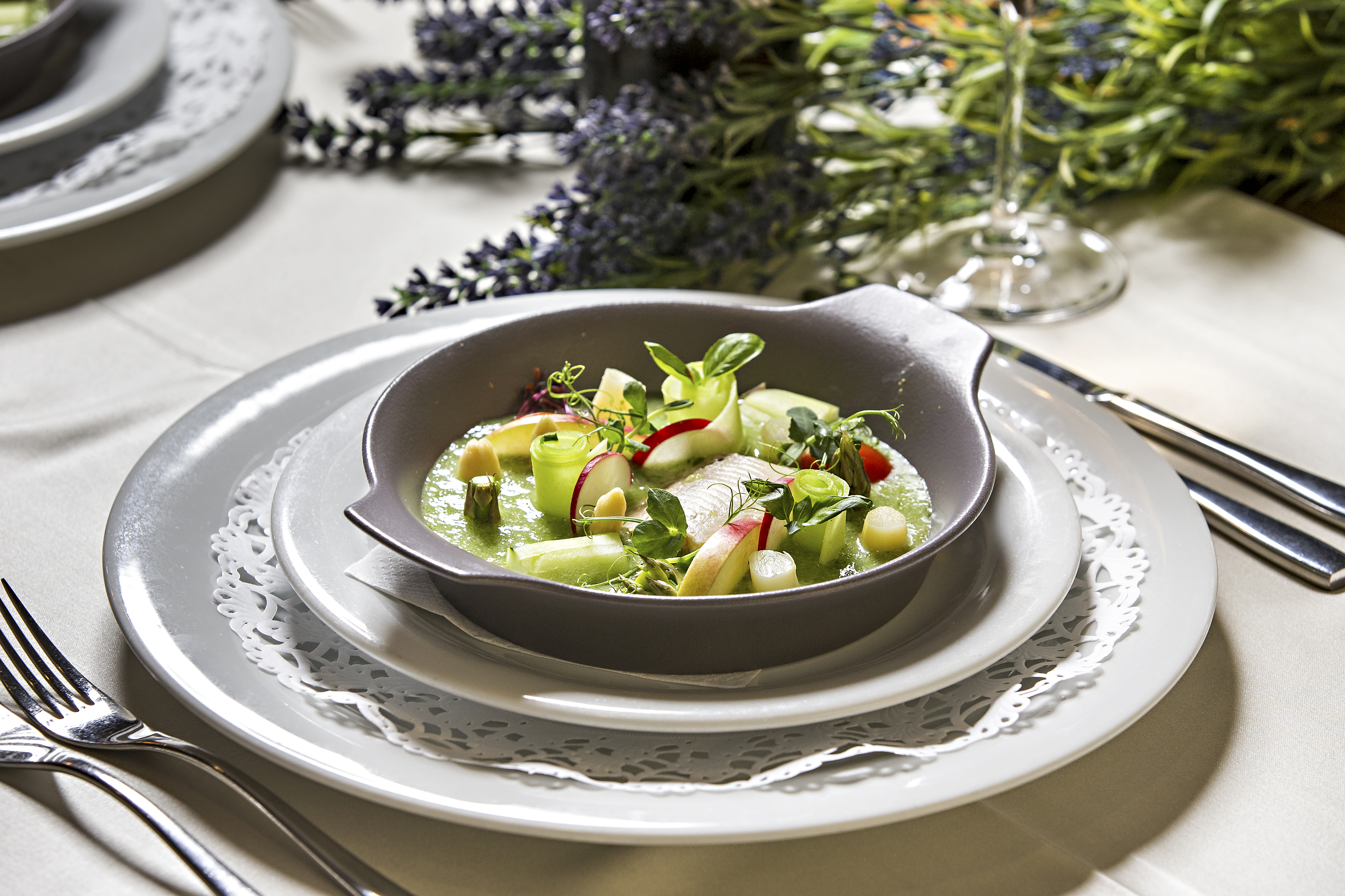 Lepo pogrnjena miza s priborom, setom krožnikov in privlačno jedjo