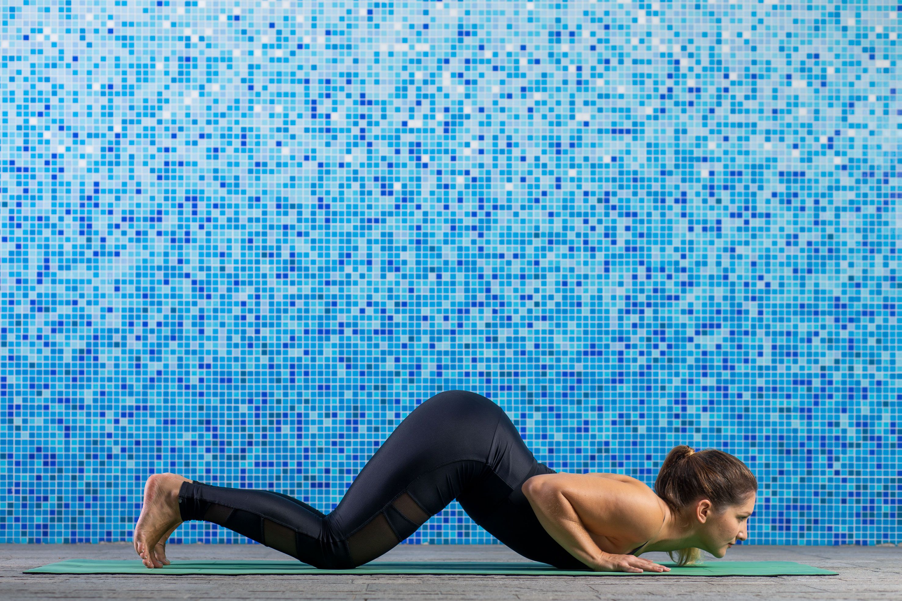 Ženska v črnih športnih oblačilih v plezajočem položaju izvaja jogo