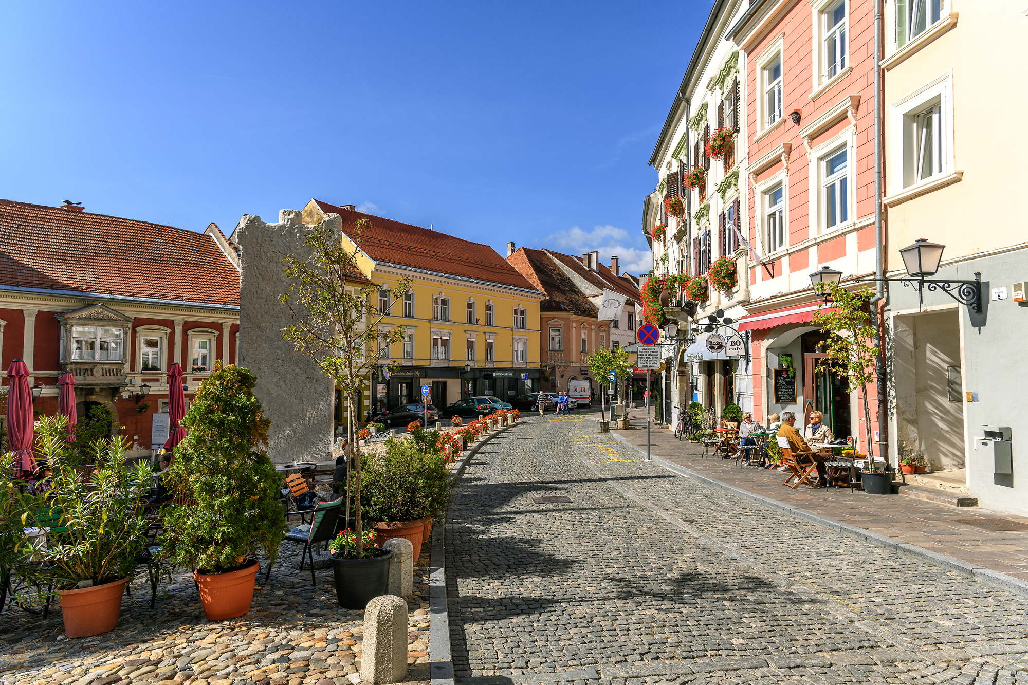 Cobbled street lined with colourful historic buildings, cafés and terraces in Ptuj’s old town.